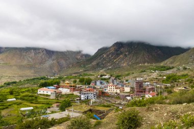 Muktinath, Mustang, Nepal 'deki Sisli Dağlar ve Uzak Evlerle Karanlık Dramatik Çöl Manzarası