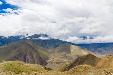 Muktinath, Mustang, Nepal 'deki Sisli Dağlar ve Uzak Evlerle Karanlık Dramatik Çöl Manzarası