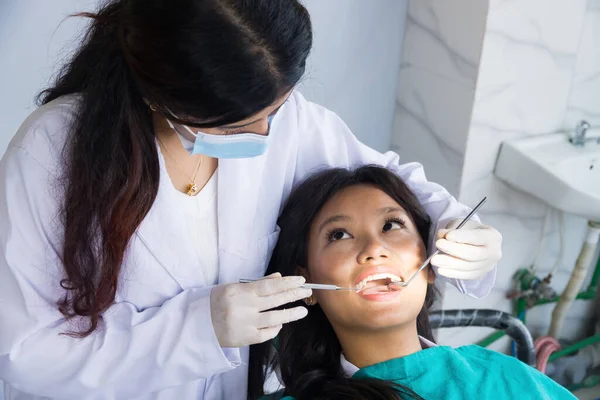 Asyalı Dişçi, hastanedeki kadın dişçi ve hastasını kontrol ediyor.