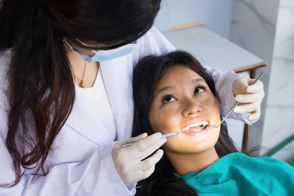 Asyalı Dişçi, hastanedeki kadın dişçi ve hastasını kontrol ediyor.