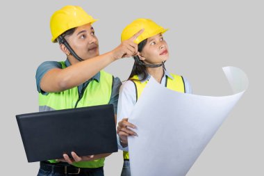 Asyalı Çift Mühendisi & Mimar, inşaat alanında dizüstü bilgisayarla hareketler ve ifadeler yapıyor