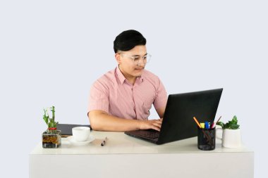 Mobil Aygıt Laptop ve Notepad ile Ön Masa Erkek Resepsiyonisti Ofis Ortamı 'nda mutluluk ifadeleri ve jestleri yapar