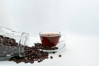 Camdan bir fincanda Espresso Americano ve taze kahve çekirdekleri izole edilmiş beyaz arka planda etrafa saçılmış.