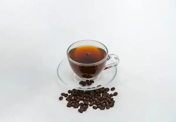 stock image Espresso Americano in a glass cup with fresh coffee beans scattered around Isolated White Background