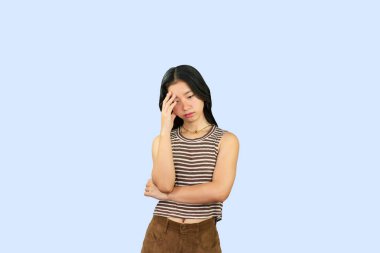 Heyecanlı Asyalı Öğrenci Kız, mavi arka planda üzgün, mutlu, gülen bir el hareketi yapıyor.