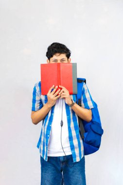 Çanta, Kitap ve kulaklıkla Yurtdışında Genç Erkek Çalışması İfade ve jestler sunar