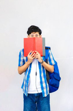 Çanta, Kitap ve kulaklıkla Yurtdışında Genç Erkek Çalışması İfade ve jestler sunar