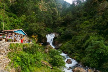 Syafrubesi, Rasuwa, Nepal - October 13 2024 : Syafrubesi to Bamboo Route in Langtang Valley Trek with Shops suspension bridge and waterfalls in front of a tea house lodge  clipart