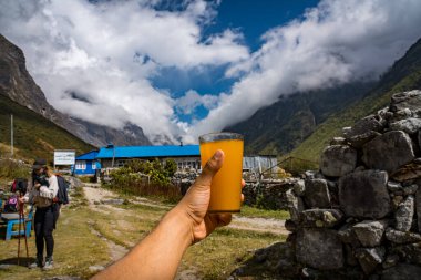 Langtang Village, Nepal - October15 2024 : Drinking Seabuck thorn juice made with warm water seabuckthorn berry and honey in the himalayan mountains of Nepal clipart