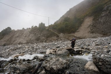 Langtang Village, Nepal - 15 Ekim 2024: Nepal yolculuğu sırasında uzak mesafedeki gezginler ve hamallarla Langtang Village 'a yaklaşmak