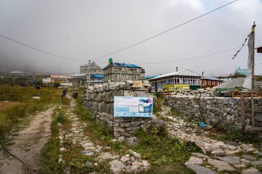 Langtang Village, Nepal - 15 Ekim 2024: Nepal yolculuğu sırasında uzak mesafedeki gezginler ve hamallarla Langtang Village 'a yaklaşmak