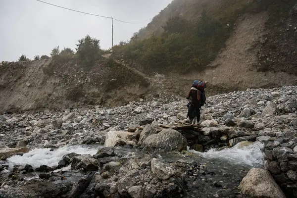 Langtang Village, Nepal - 15 Ekim 2024: Nepal yolculuğu sırasında uzak mesafedeki gezginler ve hamallarla Langtang Village 'a yaklaşmak