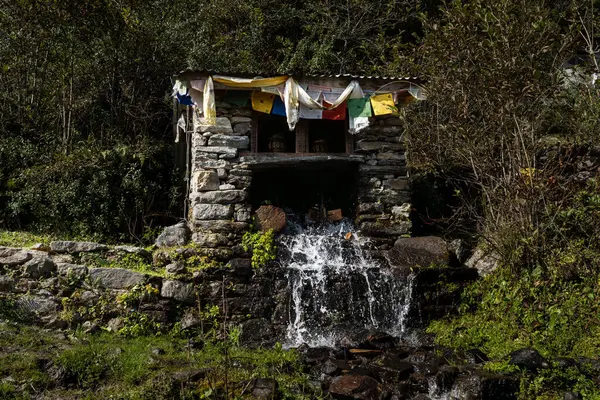 Taş yapısı Nepal 'de şelalesi ve Budist bayrakları olan küçük hidro jeneratörü. 