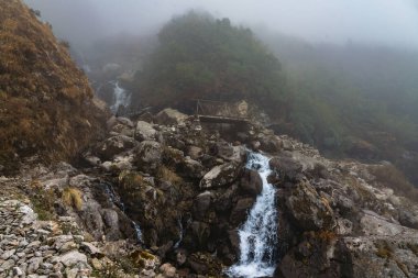 Nepal 'in Langtang bölgesinde bir köprüsü olan dağlardaki güzel Himalaya Buzul Şelaleleri.