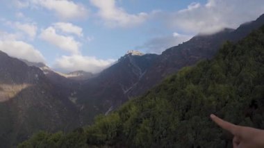 Sabahın erken saatlerinde yeşil dağlarla birlikte bulutlar ve gölgelerle dolu engebeli bir dağ silsilesi.