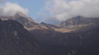 Sabahın erken saatlerinde yeşil dağlarla birlikte bulutlar ve gölgelerle dolu engebeli bir dağ silsilesi.