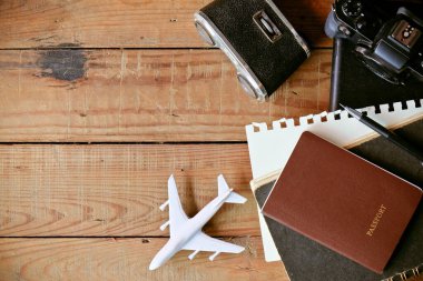 Pasaport, kamera, defter ve uçakla seyahat kavramı ahşap arka planda