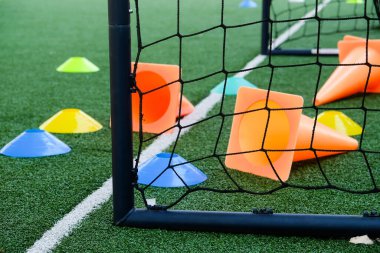 Futbol golü ve koniler yeşil suni çim, spor arka planı.