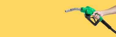 Sarı arka planda yakıt hortumunu tutan eller