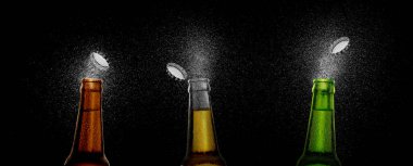 Siyah arka planda bira damlatan üç bira şişesinin yakın plan fotoğrafı. Bira kapağı şişenin üstünde uçuyor.