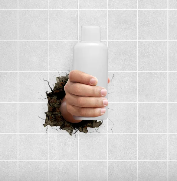 Tangan Manusia Memegang Botol Kosmetik Melalui Dinding Dengan Retakan — Stok Foto