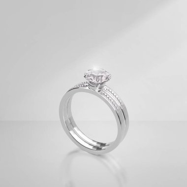 Açık arkaplanda gölgeli zarif elmas bir yüzük.