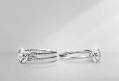 Açık arkaplanda gölgeli zarif elmas bir yüzük.