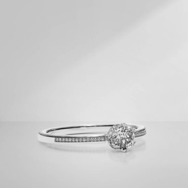 Açık arkaplanda gölgeli zarif elmas bir yüzük.