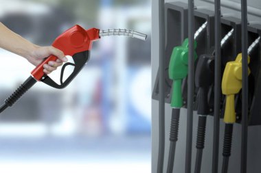 Adam benzin hortumunu arka planda bulanık bir benzin istasyonunda tutuyor.