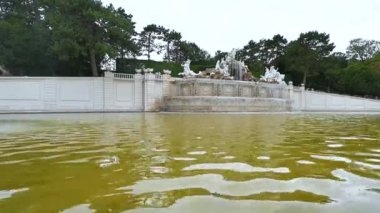 Viyana, Avusturya, Ağustos 2022. Schonbrunn saray bahçelerinde inanılmaz görüntüler var. Çeşmenin büyük su kütlesindeki eğim hareketi bir grup heykel tarafından aşıldı..