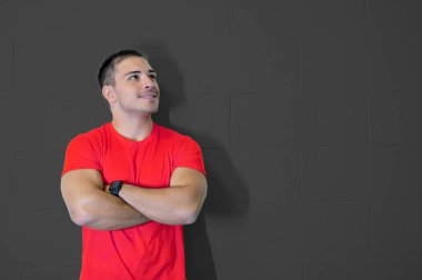 Beyaz tenli genç bir sporcunun kollarını kavuşturup gülümseyerek yan tarafa baktığı güzel bir resim. Kendinden emin ve olumlu başarı kavramı. Gol başarısı. Boş duvar, boşluğu kopyala.