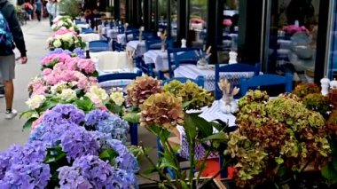 Viyana, Avusturya, Ağustos 2022. Naschmarkt pazarında yavaş çekimde çekilmiş, market boyunca uzanan restoranlardan birinin masasının manzarası. Öndeki saksılar, arkadaki müşteriler...