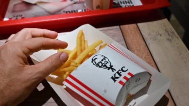 Viyana, Avusturya, Ağustos 2022. KFC patates kızartmasının yavaş çekim görüntüleri. El paketten bir patates cipsi alıyor..