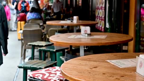 ウィーン オーストリア 2022年8月 ナシュマルクト市場のスローモーション映像 市場に沿ってレストランのテーブルのビュー 手前の木のテーブル 奥の人たち — ストック動画