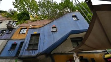 Viyana, Avusturya, Ağustos 2022. Viyana 'daki Hundertwasser evinin bitkileri ve ağaçlarıyla dolu renkli yüzün inanılmaz görüntüleri. Konut, apartman. Pan hareketi, hayır çocuk..
