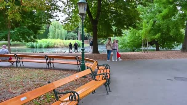 ウィーン オーストリア 2022年8月 非常に中央Stadtpark都市公園で素敵なスローモーション映像 人々は道に沿って歩くか 長い線で配置された特徴的なベンチに座っています 庭のデザイン — ストック動画