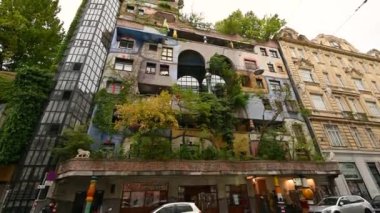 Viyana, Avusturya, Ağustos 2022. Viyana 'daki Hundertwasser evinin bitkileri ve ağaçlarıyla dolu renkli yüzün inanılmaz görüntüleri. Konut, apartman. Eğim hareketi.