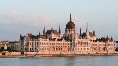 Budapeşte, Macaristan, Ağustos 2022. Tuna Nehri tarafından parlamentonun dörtte üçlük manzarası çarpıcı. Öğleden sonranın sarı ışığı yüzümü ısıtıyor..