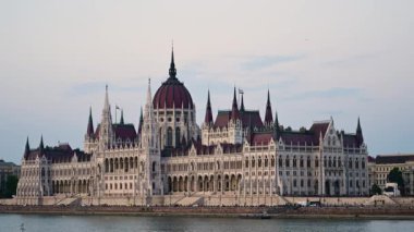 Budapeşte, Macaristan, Ağustos 2022. Tuna Nehri tarafından parlamentonun dörtte üçlük manzarası çarpıcı. Öğleden sonranın sarı ışığı yüzümü ısıtıyor..