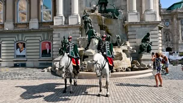 ブダペスト ハンガリー 2022年8月 ブダ城のマティアス噴水の前で2頭の馬の警備員のスローモーション映像 観光客は記念写真を撮る 天気の良い日 — ストック動画