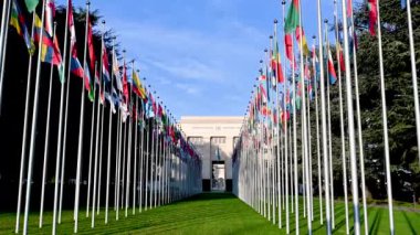 Geneva, Switzerland, January 2023. Wide-angle lens and low-angle footage giving an iconic image of the United Nations headquarters. In the courtyard the flags of the member states are waving.