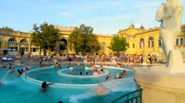 Budapeşte, Macaristan, Ağustos 2022. Szechenyi Hamamı 'nın su özellikli havuzlarından birinin güzel bir görüntüsü. İnsanlar pistte yürürken eğleniyor. Güzel bir yaz günü.
