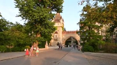 Budapeşte, Macaristan. Ağustos 2022. Baş döndürücü POV görüntüleri Gatehouse Kulesi 'nin girişine doğru yürüyor, sıcak öğleden sonra ışığı ön cepheyi aydınlatıyor. Güzel bir yaz günü, insanlarla karşılaşıyoruz..