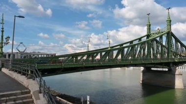 Budapest, Hungary, August 2022. Beautiful wide angle lens footage of the Freedom Bridge on a beautiful summer day. Iconic image of the big green bridge with the white clouds in the background. Pan.