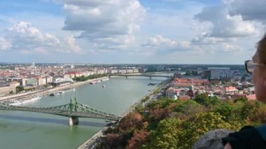 Budapeşte, Macaristan, Ağustos 2022. Şehrin hava manzaralı güzel bir görüntüsü var. Orta yaşlı bir kadın etrafına bakar ve cep telefonuyla fotoğrafını çeker..