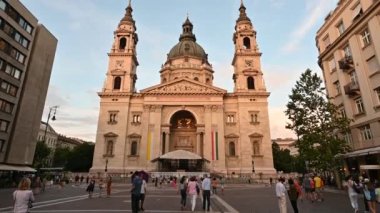 Budapeşte, Macaristan, Ağustos 2022. St. Stephen Bazilikası 'nın sıcak öğleden sonra ışığıyla aydınlatılan görüntüsü inanılmazdır. İnsanlar meydanda yürür.