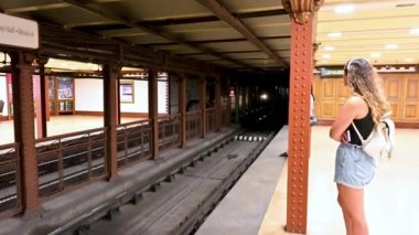 Budapest, Hungary, August 2022. A young woman is waiting for the m1 metro, the historical first line of the city. A convoy arrives at the opposite quay.