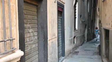 Cenova, Liguria, İtalya. 3 Haziran 2023. Tarihi merkezde Caruggio adında yerel dilde bir ara sokağa ait büyüleyici görüntüler. Orta yaşlı bir kadın bunu araştırıyor ve Ceneviz 'i keşfediyor..