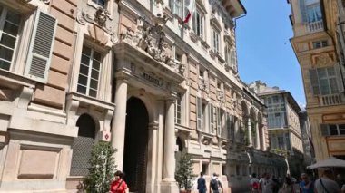 Cenova, Liguria, İtalya. 3 Haziran 2023. Tarihi merkezdeki belediye binasının büyüleyici görüntüleri. Güzel bir yaz gününde insanlar cadde boyunca yürür. Ceneviz 'i keşfedin..
