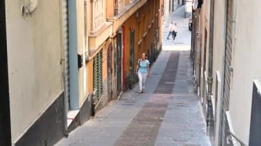 Cenova, Liguria, İtalya. 3 Haziran 2023. Tarihi merkezde Caruggio adında yerel dilde bir ara sokağa ait büyüleyici görüntüler. Orta yaşlı bir kadın bunu araştırıyor ve Ceneviz 'i keşfediyor..